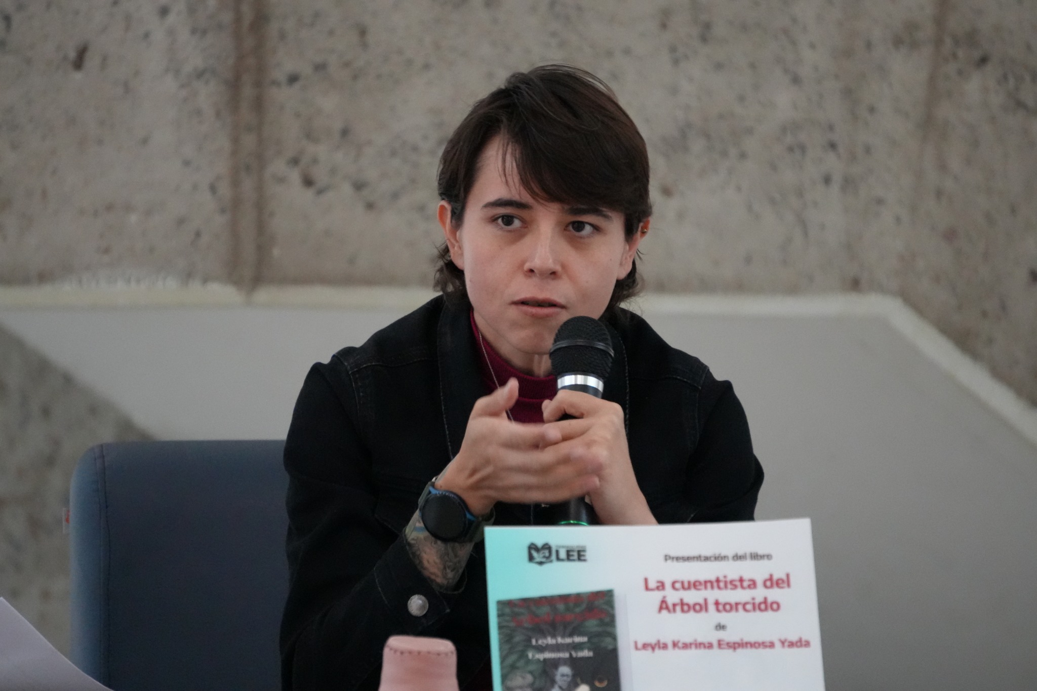 Leyla Karina Espinosa Yada habla con un micrófono durante la presentación de su libro.