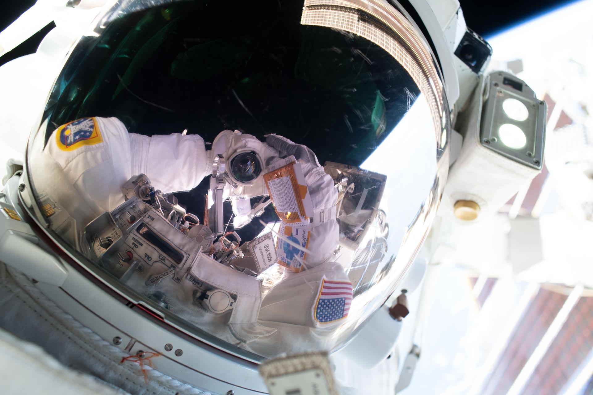 Anil Menon reflejado en el visor de su traje durante una caminata espacial del 25 de agosto de 2026.