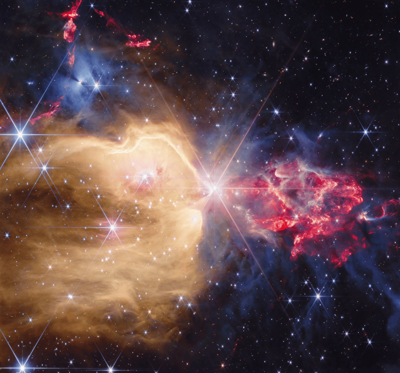 Captura infrarroja de NGC 7129 con estrellas, nubes doradas y flujos de gas rojizos